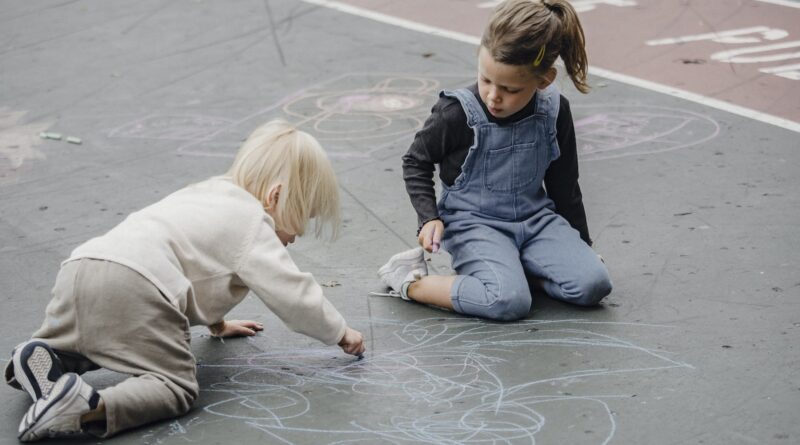 Adorable girls drawing on asphalt